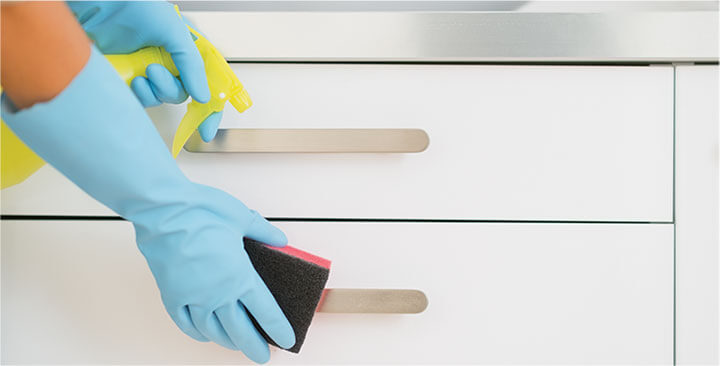 photo of a cleaner cleaning a kitchen counter with blue plastex gloves on